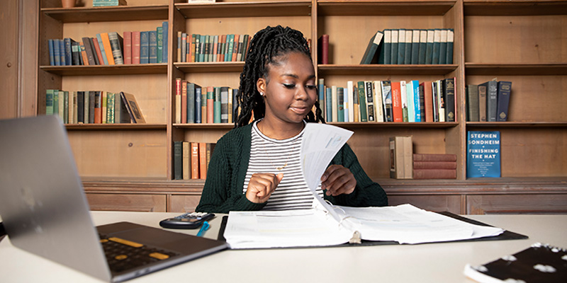 Student studying with notebook and laptop