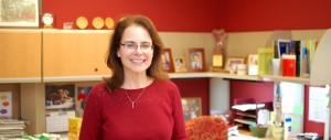 Dr Frick standing and smiling in an office with bookshelves, framed photos, and a red accent wal