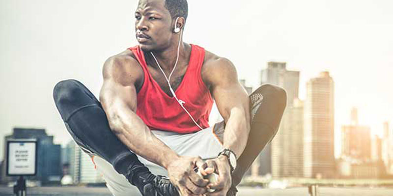 Runner stretching outside listening to headphones