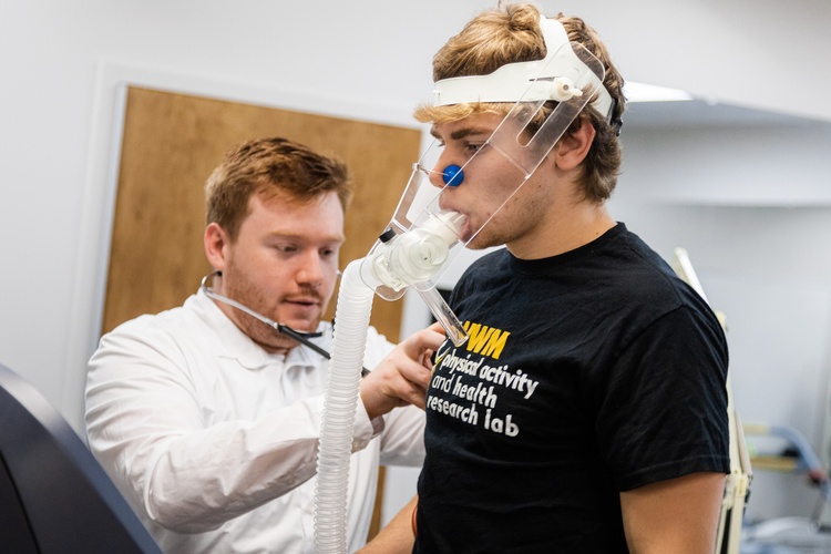 Kinesiology master's student practices evaluating a students oxygen usage.