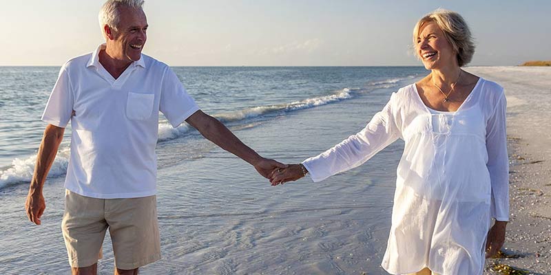Man and woman holding hands walking on the beach
