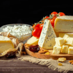 A table spread with an assortment of cheeses, and cherry tomatoes.