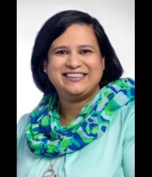 Headshot of Dr. Rochelle Mendonca smiling, wearing a teal blouse and a blue-green patterned scarf against a light gray background.