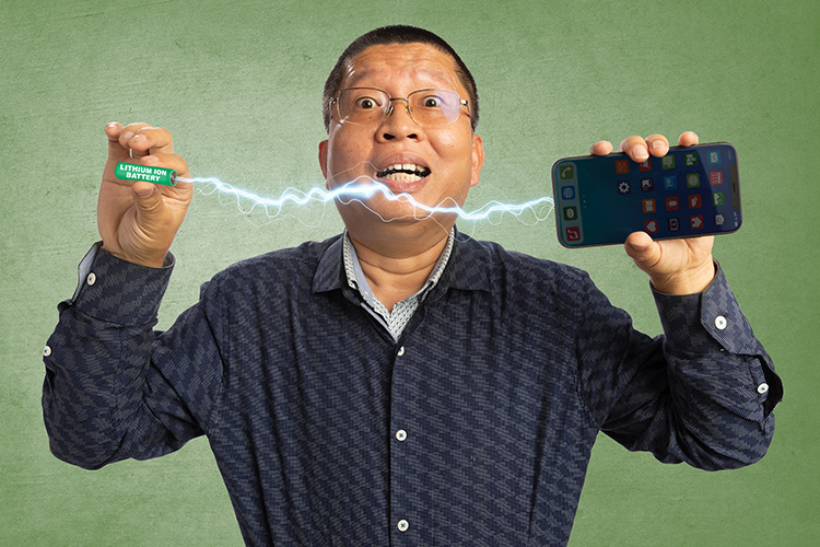 person holding battery and phone with "electricity" between