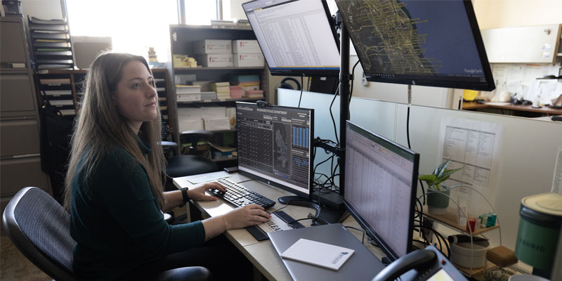 Crime analyst Alexa Voelz works at her desk among four screens that display real-time data.