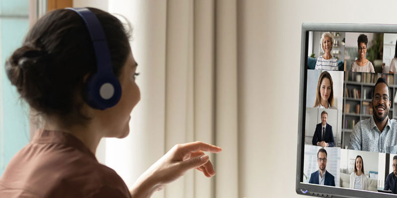 A young woman wearing headphones and interacting with a video chat on her computer