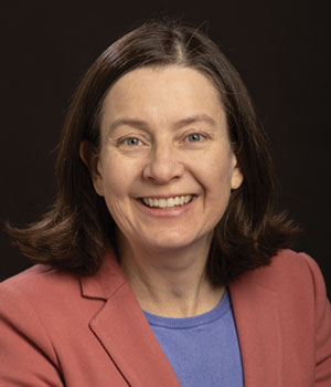Headshot of white female professional with rose-colored blazer.