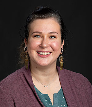 PhD Student Lane Morein wearing a sweater and dangling earrings.