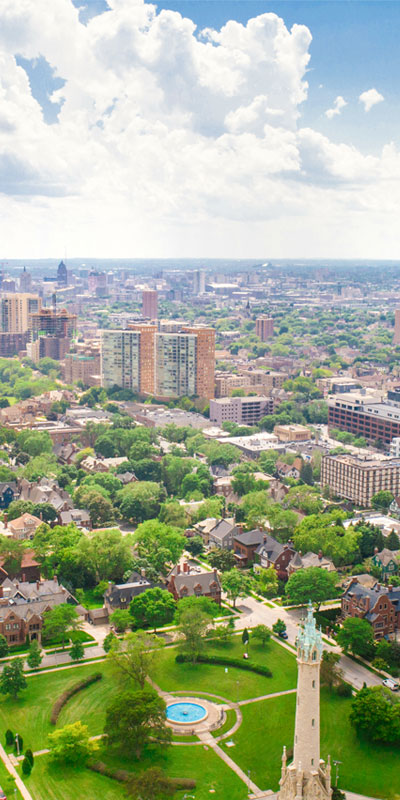 Aerial drone photo of the East Side of Milwaukee showing green park, water tower, and the city stretching off into the horizon.