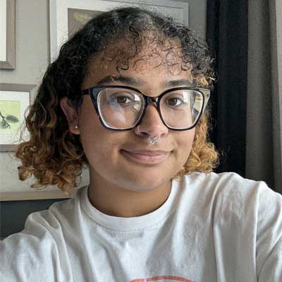 Graduate student (bi-racial female) with short hair and glasses looking at the camera.