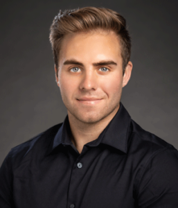 Headshot of white male doctoral student in black button up shirt.