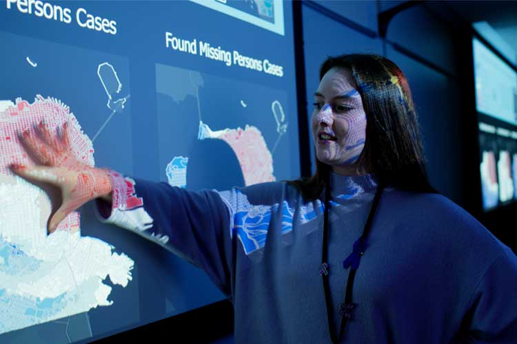 Professional female (white) standing in front of a map projected on the wall.