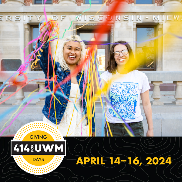 Two females students celebrate tossing colorful streamers into the air outside of a traditional-looking campus building with columns and brick.