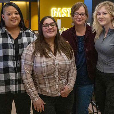 Social work student association at UW-Milwaukee includes three females (Asian, Latina and white) and a faculty member standing together in the student union.