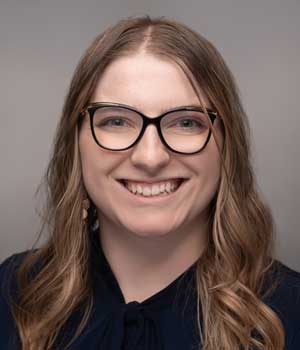 Headshot of young female graduate student wearing glasses and a black blouse.
