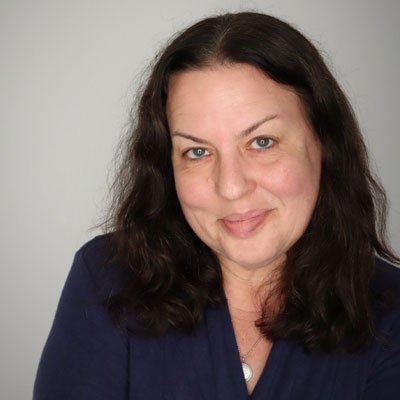 Clinical Associate Professor Jen Kahn-Pettigrew wearing a necklace and a V-neck sweater.