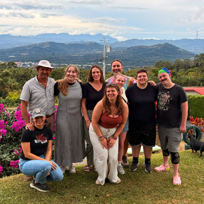 Students and instructors standing on a lawn with Costa Rican mountains in the background.