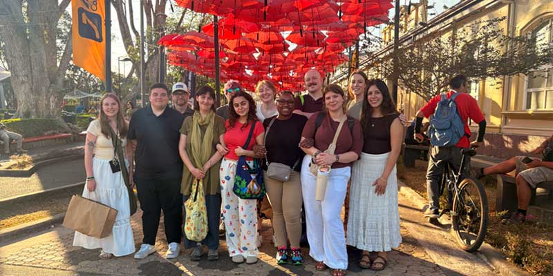 Students standing below a canopy of red umbrellas in Costa Rica.