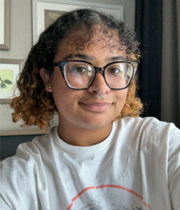 Graduate student (bi-racial female) with short hair and glasses looking at the camera.