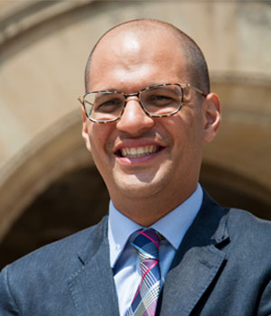 Headshot of white male standing outside with the Milwaukee County Courthouse behind him.