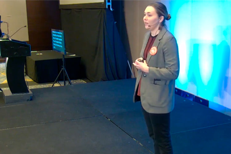 Woman standing on stage giving a Brief & Brilliant talk at SSWR.