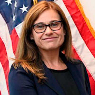 Portrait of Kimberly Hassell (white woman), criminal justice & criminology associate professor posing in front of an American flag.