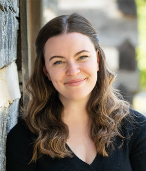 Criminal Justice & Criminology Teaching Faculty Elizabeth Lyne leaning against a wall outside.