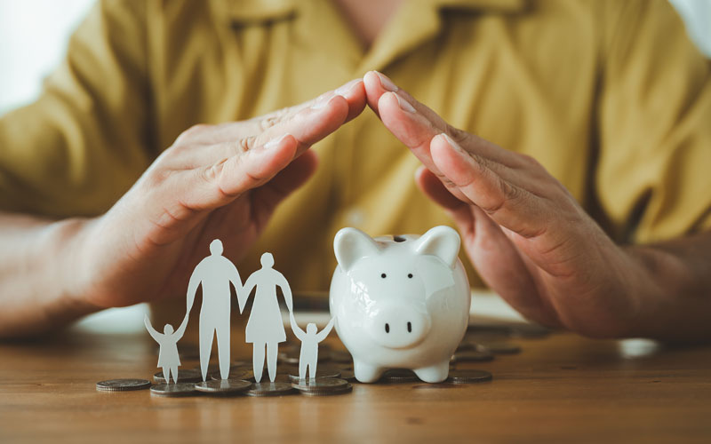 Hands over piggy bank and family cutout