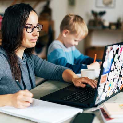 parent studying at laptop with child nearby