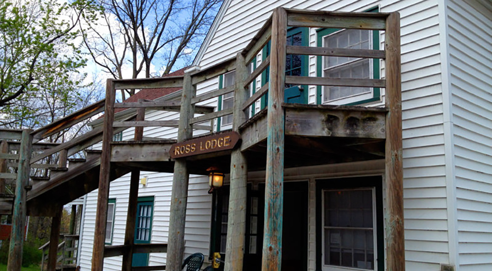 Photo of an exterior of a two story high house. A wooden porch runs along the entire second floor