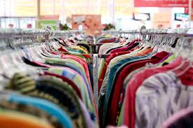 Two rows of shopping racks filled with clothing. The perspective of the camera is too close to make out many details of the clothing outside of the wide variety of colors represented