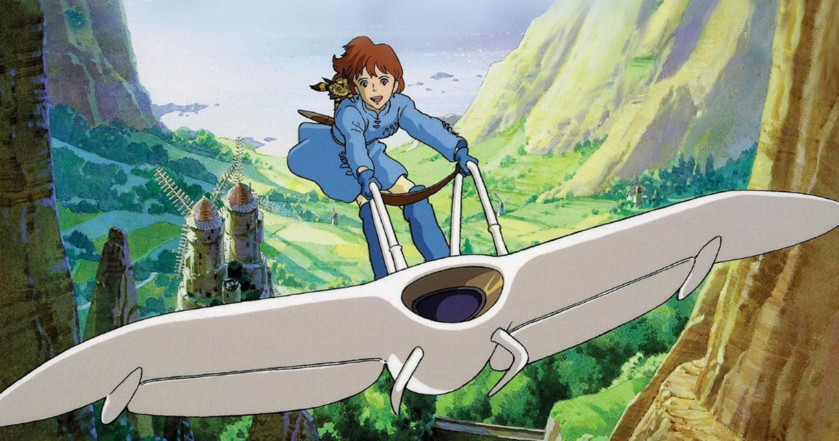 An anime still from Nausicaä of the Valley of the Wind showing Nausicaä, a young woman with short reddish-brown hair wearing a blue tunic and pants, flying her white, bird-like glider (the Mehve) through a lush green valley. She stands upright on the glider, holding onto its control bars, with a small, fox-squirrel creature perched on her shoulder. In the background, green cliffs and distant towers rise under a partly cloudy sky.