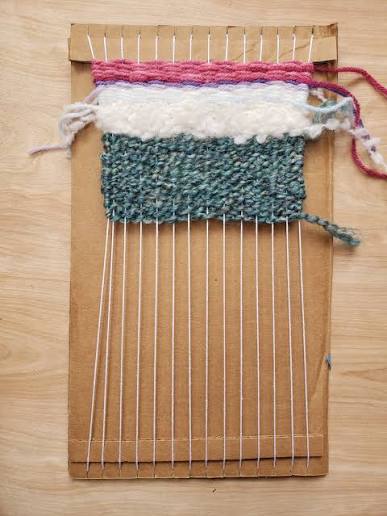 Handmade cardboard weaving loom with colorful yarn.
