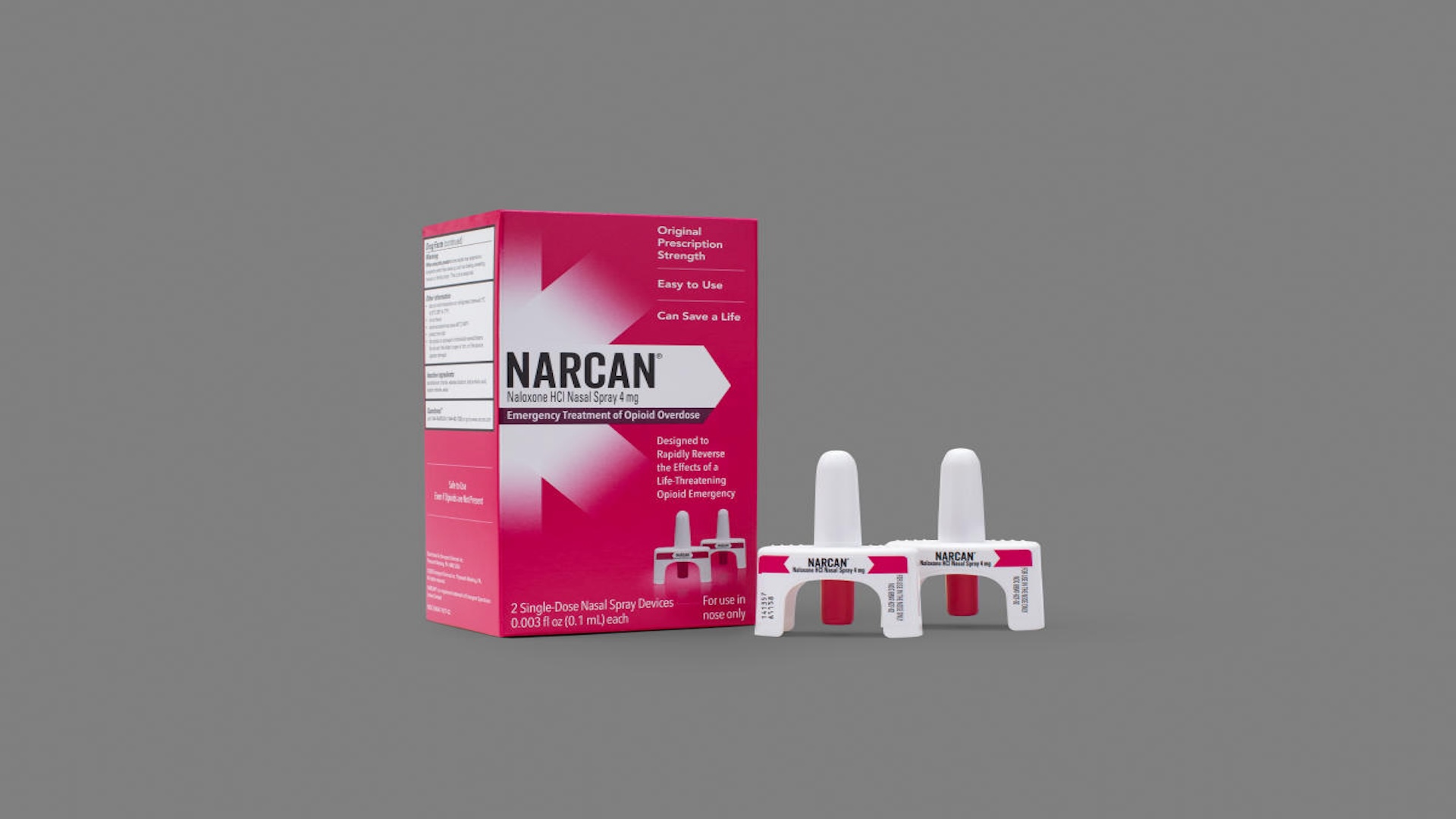 A box of Narcan nasal spray next to two single-dose nasal spray devices against a plain grey background.