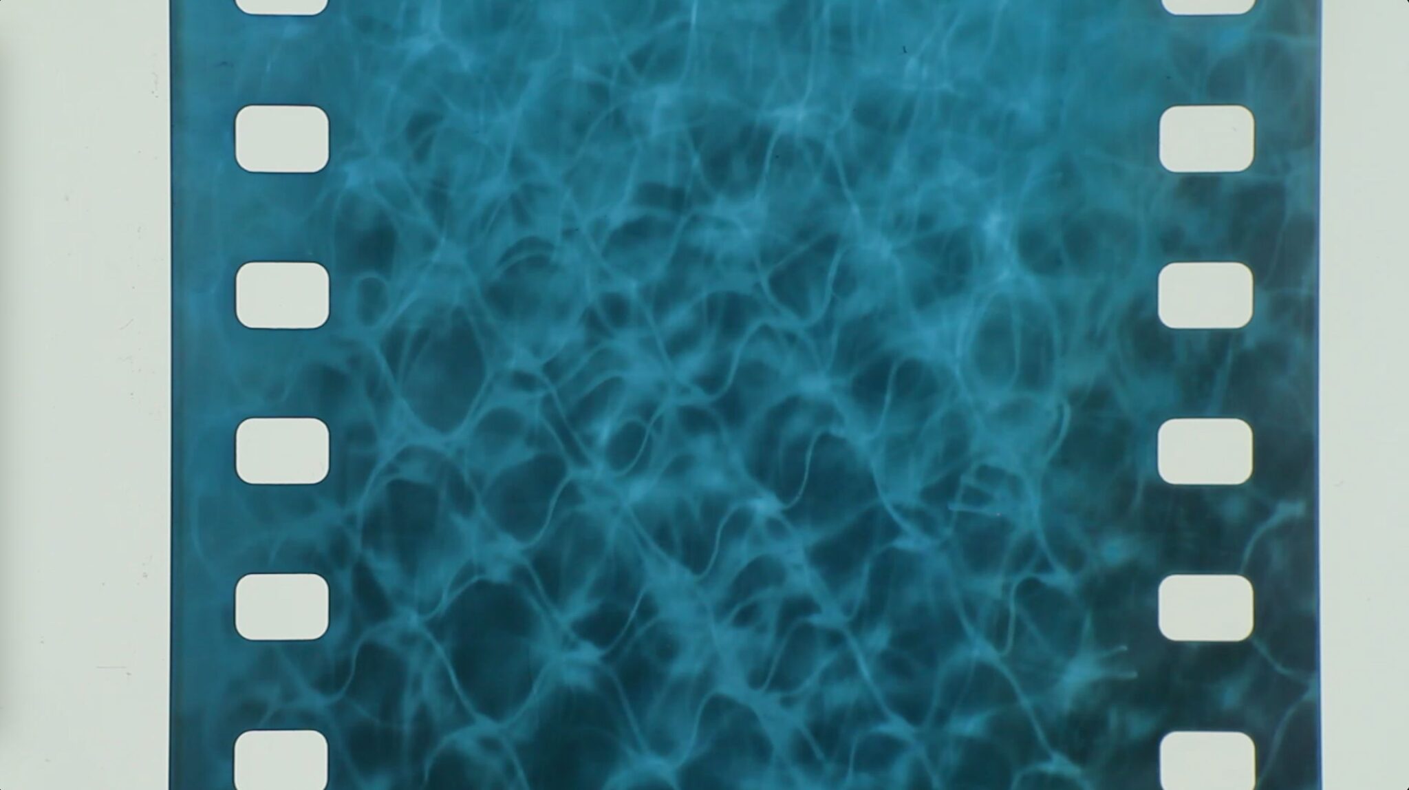 A frame of a 35mm film strip against a dark background, showing a blue abstract textured pattern between white sprocket holes.