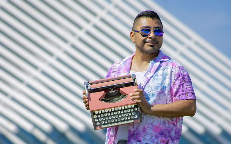 John Contreras outside Milwaukee Public Art Museum holding a pink typewriter