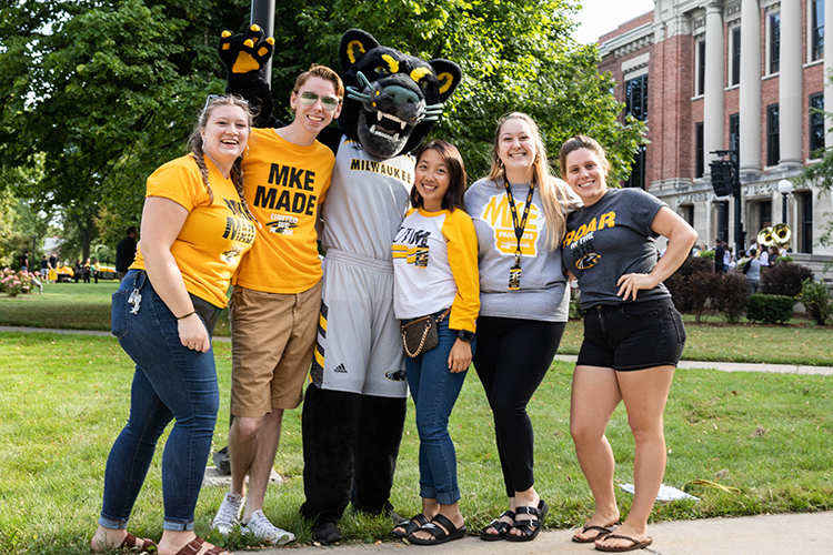 A group of students wearing UWM gear posing with Pounce, the UWM mascot