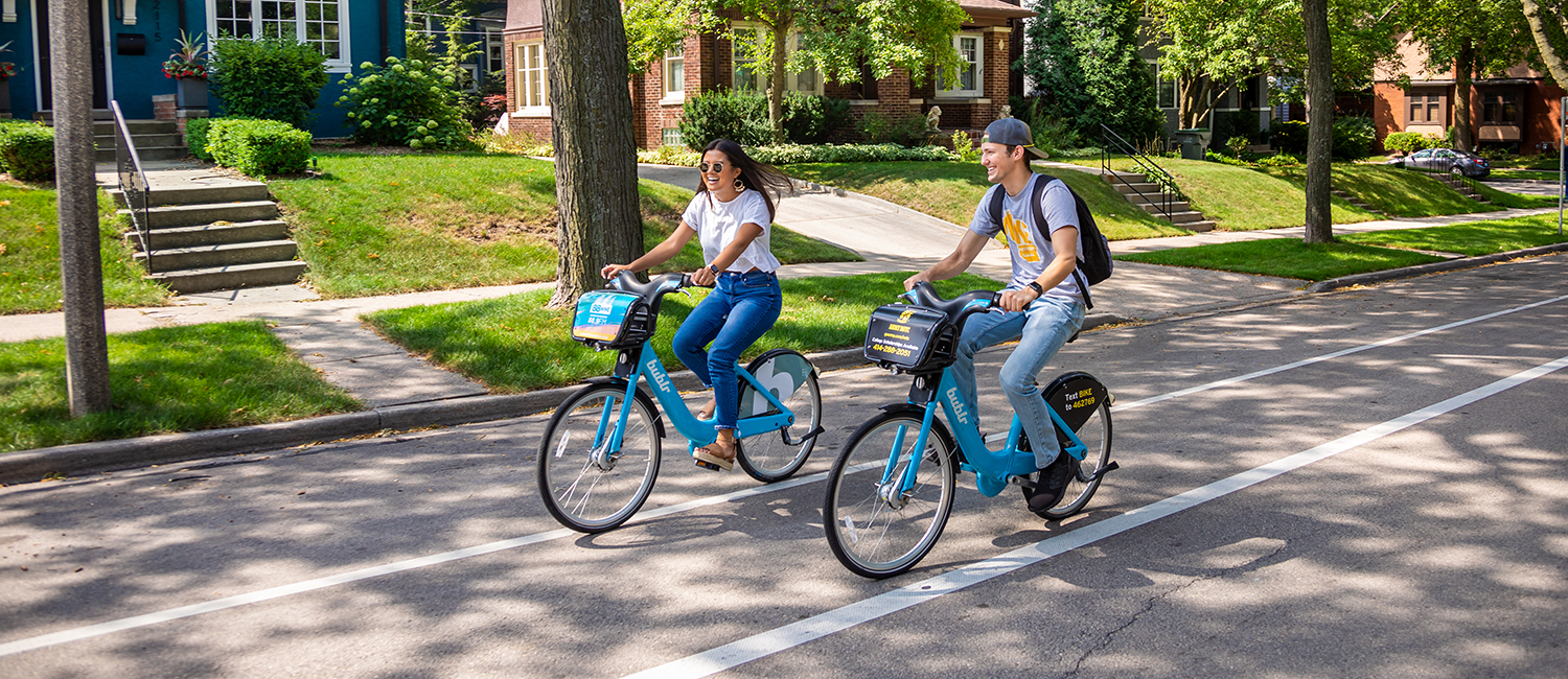 Young man and young woman riding bikes on a street in the summer