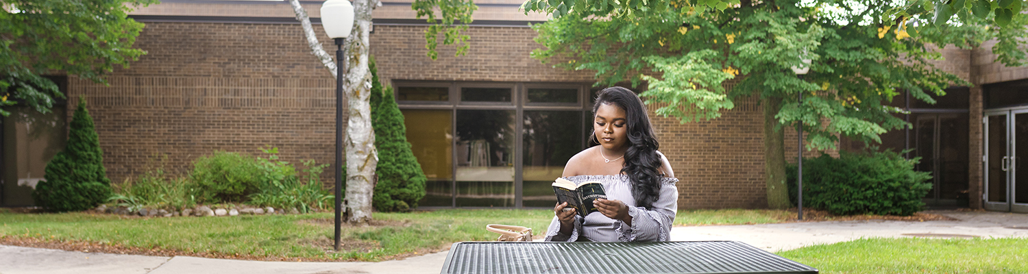 UWM student sitting outside reading a book