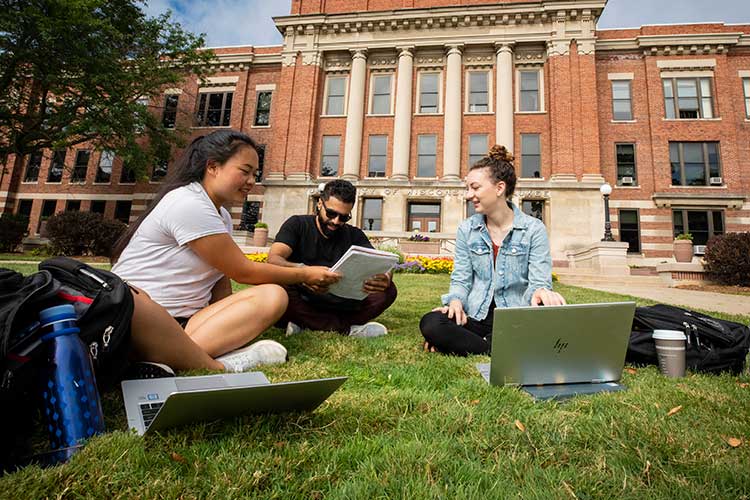 Students outside working on computers in front of Mitchell Hall