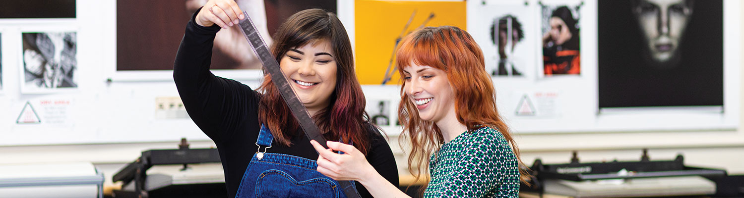 Student reviewing film strip with UWM professor in the photography lab