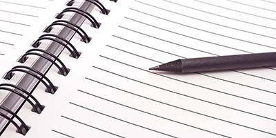 A photo of a black pen laying across a blank open notebook