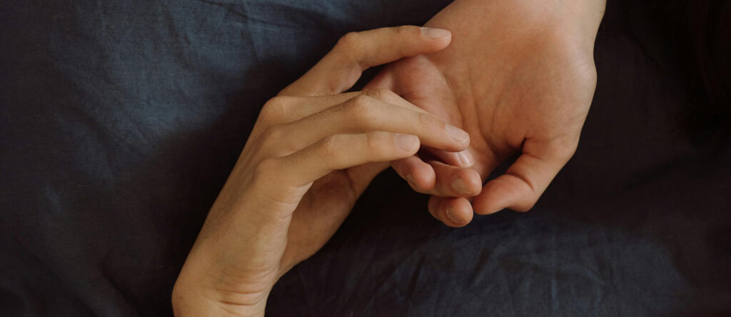 Two hands touching on a bed