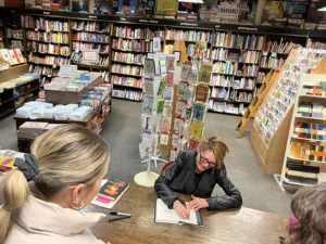 Author signing a book for an attendee at a bookstore event