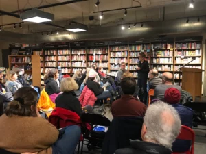Audience seated in a bookstore listening to a speaker during RPI book launch event