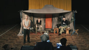 people on a stage in a tent as in a war setting