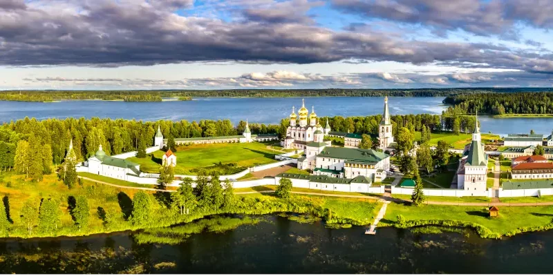 Aerial view of a monastery complex on a green island surrounded by a lake.