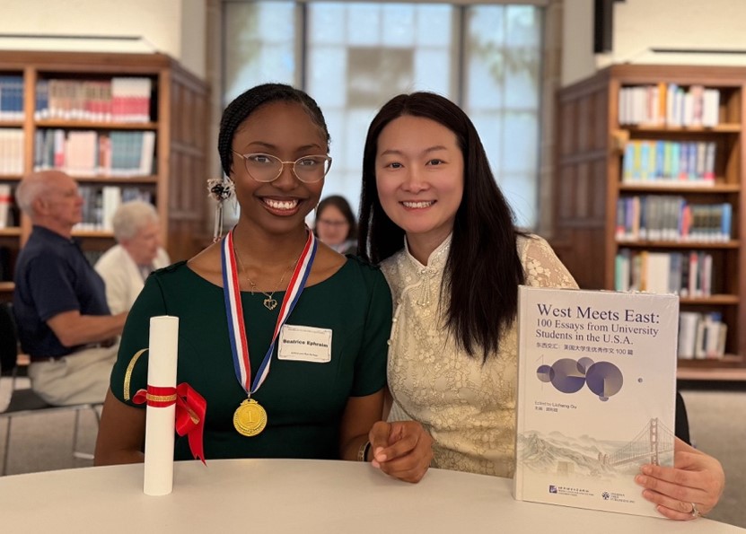 Beaming gold medalist Beatrice Ephraim celebrates her win with her mentor, Lu Yin, while showcasing her certificate and prizes.  