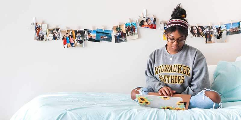 Student sitting on her bed in her dorm room