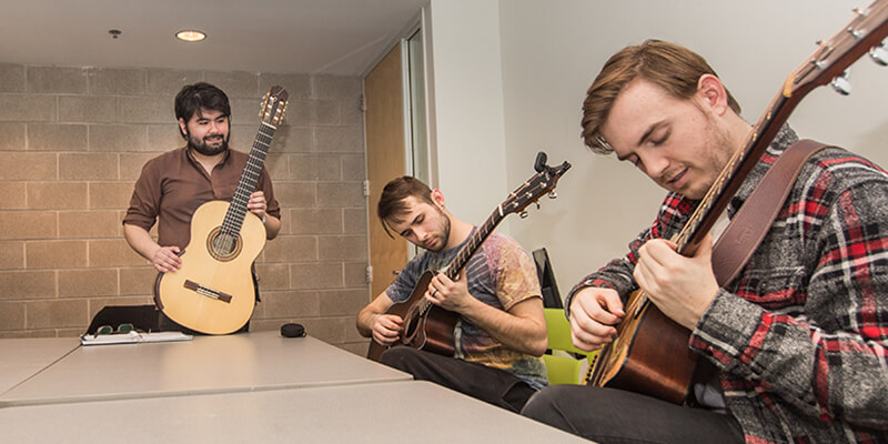 Three students playing guitar